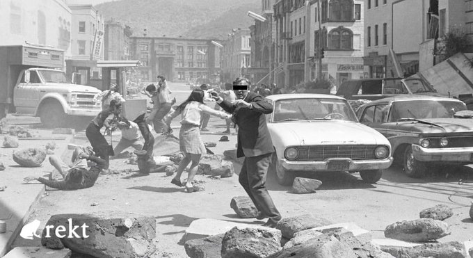 A dramatic black-and-white still shows chaos in a city street as a man in a suit fires a gun amid scattered debris, vintage cars, and panicked civilians — evoking a heist-style "attack" scene that visually mirrors the $120.4M exploit of @TectonicFi on @CronosNetwork, where $9.19M of stolen funds escaped unrecovered. The "rekt" watermark in the corner reinforces the parallel to rekt.news coverage of the hack.