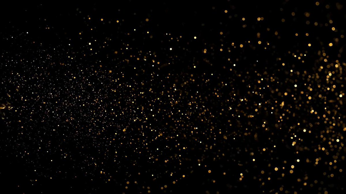 The image features a large black screen that displays an array of gold and diamond particles scattered across its surface, creating a sense of depth and movement. The background of the image is completely black, with a white stripe running down the middle, which further accentuates the prominence of the particles on the screen. The overall composition gives off the impression of a space filled with cosmic dust or particles.