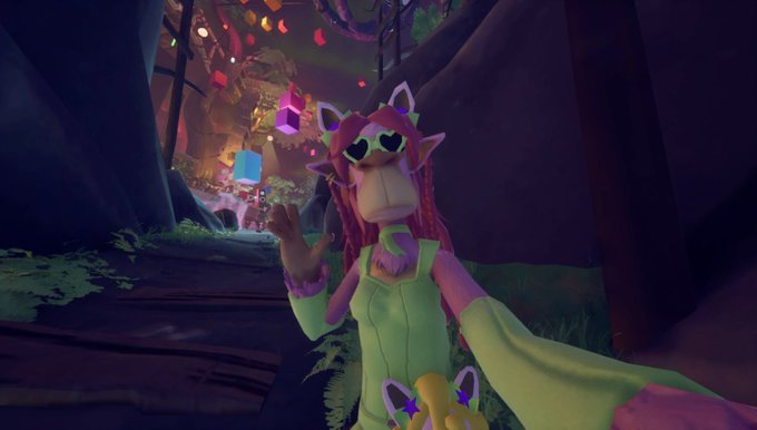 A first-person view from a video game showing a colorful character with pink hair, heart sunglasses, and a party hat posing in a festive, cave-like environment.