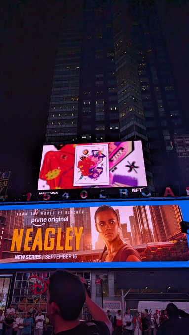 A nighttime cityscape featuring illuminated billboards, including a 'prime original NEAGLE' series advertisement (New Series | September 16) and a '1954 OOR NFT' display, with a crowd of people visible at street level.