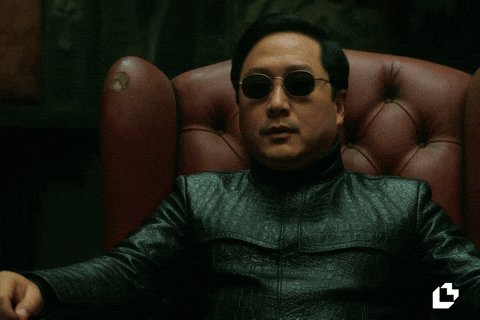 The image shows a man sitting in a leather chair, wearing sunglasses and a black jacket with crocodile skin-like details. The man appears to be gazing at something off-camera or not looking directly at the viewer. Below him on the image, there is text that says "Me ignoring the huge crypto price drop and focusing just on rising $LTC pairs:". This implies that the man in the chair might have been paying attention to a specific cryptocurrency that has seen a rise in value recently, possibly related to the real estate market or another type of investment.