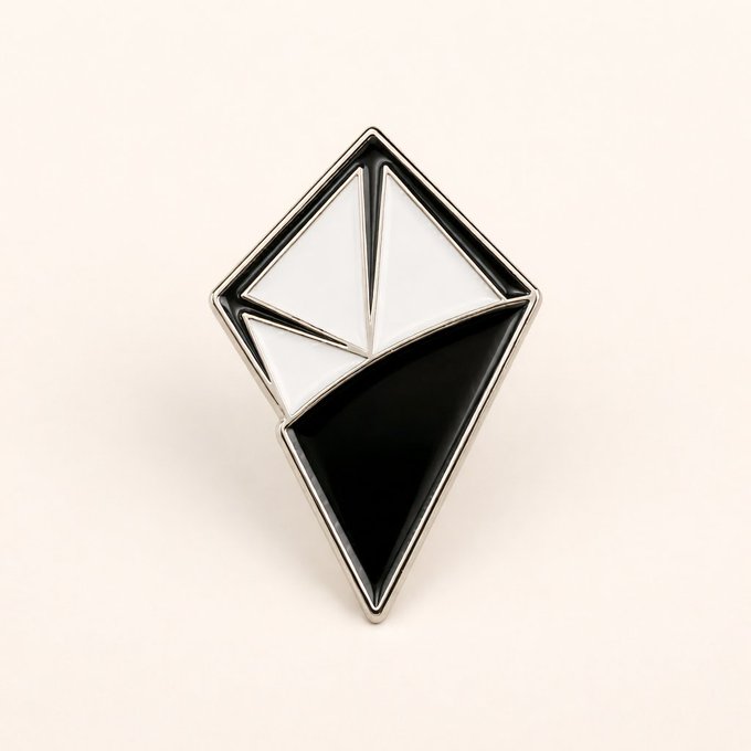 A black and white enamel pin shaped like a geometric diamond or crystal.