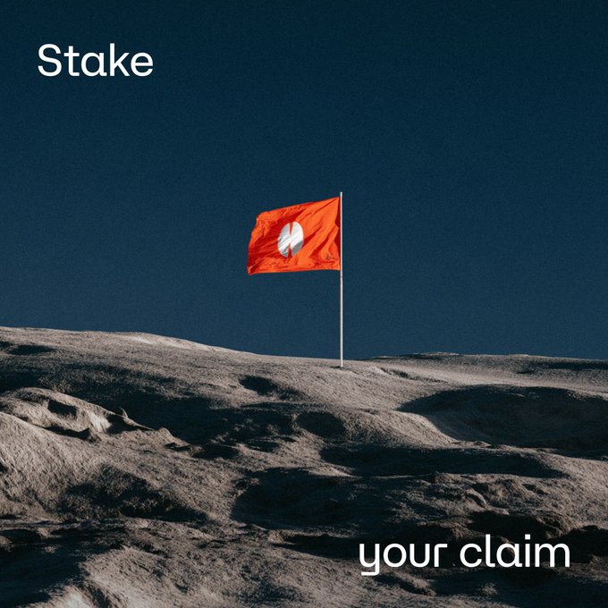 A red flag with a white logo is planted on a rocky, moon-like surface against a dark sky, with the text 'Stake' in the upper left and 'your claim' in the lower right.