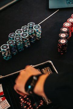 A person wearing a smartwatch reaches for poker chips from a case at a table stacked with neatly arranged blue and red chip towers, capturing the high-stakes atmosphere of the Solana poker night.