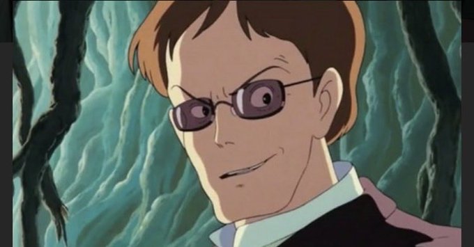 A close-up anime-style illustration of a smiling man with brown hair and rectangular glasses, wearing a pink shirt and dark jacket against a textured green background.