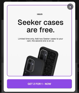 A promotional pop-up ad with the text 'SOLYD', 'Seeker cases are free.', 'Limited time only. Add two Seeker cases to your cart, the second one is on us.', and a button reading 'GET 2 FOR 1 - NOW', displaying two black phone cases.