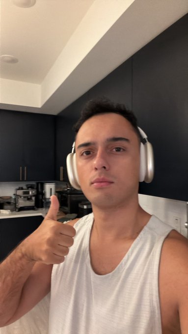 A man wearing a tank top and over-ear headphones gives a thumbs-up in his kitchen, signaling his bullish mood as Bitcoin hits $71K and crypto markets surge. The caption emphasizes waking up early to check the charts, reinforcing excitement for the bull market.