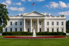 The White House, the official residence of the U.S. President, photographed on a clear day with its iconic North Portico, fountain, and red, white, and blue landscaping visible.