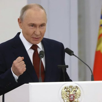 Vladimir Putin is pictured giving a speech at a podium featuring the Russian coat of arms, appearing to react emphatically to the news that Russia is legalizing Bitcoin and cryptocurrency trading.