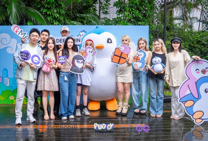 A group photo at a DEEPCOIN x PUDGY PENGUINS x QQ event, featuring people holding character cutouts alongside a large penguin mascot.