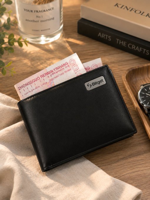 The image features a black wallet sitting on top of a wooden table, with a book next to it. The wallet has a label that says "Bigr" on it. There are also two books visible in the scene - one placed near the wallet and another further away from the wallet. A bottle can be seen at the edge of the image as well.