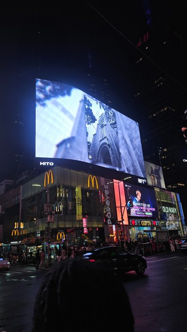 Nighttime street view of a bustling city intersection featuring large illuminated digital billboards, McDonald's signs, and advertisements for 'Old Navy', 'CVS', and others.