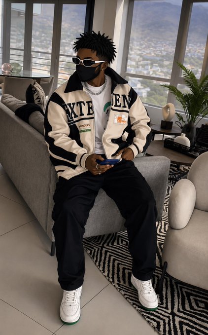 A 3D-rendered figure wearing sunglasses, a face mask, and a black and white letterman jacket with 'EXTEN' and Bitcoin logos, sitting on a couch holding a blue phone.