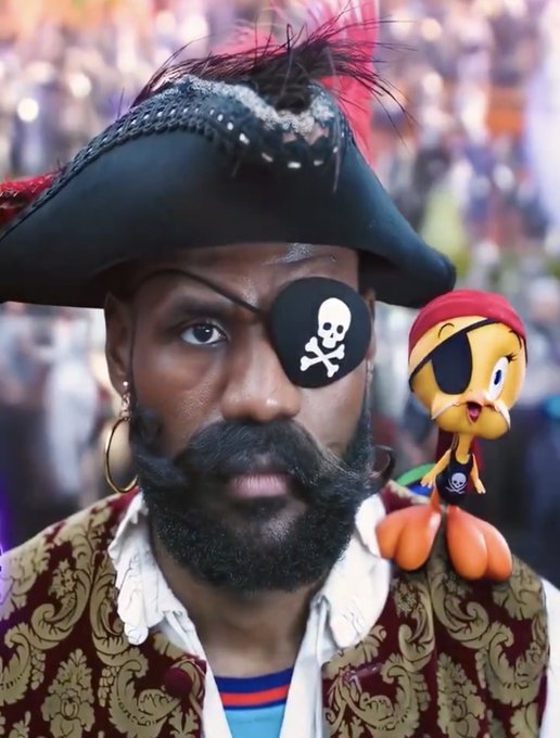A man dressed as a pirate with an eyepatch, mustache, tricorn hat, and ornate jacket, with a Tweety Bird character dressed as a pirate sitting on his shoulder.