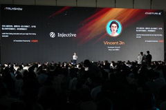 A conference presentation showing 'Injective' and 'Vincent 3n' on the screens above an audience seated in a darkened hall.