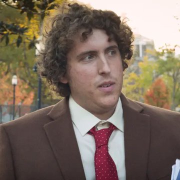 A curly-haired man in a brown suit, white shirt, and red patterned tie is shown in a close-up outdoor shot with autumn foliage in the background, appearing to speak in an interview setting. The image appears to depict Andrew Callaghan, the journalist referenced in the post about Channel 5 sharing its subscriber list with Hunter Biden.