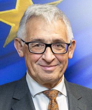 Piero Cipollone, Executive Board member of the European Central Bank, is shown in a headshot portrait against the backdrop of the EU flag with its circle of yellow stars on blue. The image accompanies news of his warning that stablecoins are draining European bank deposits, with his official position lending authority to concerns about Europe's growing dependence on alternative payment providers.