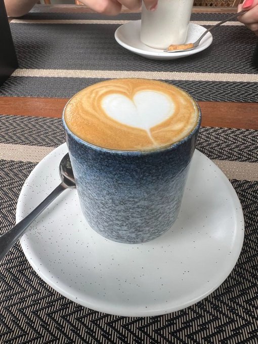 A steaming cup of coffee with heart-shaped latte art sits on a speckled saucer atop a patterned placemat, perfect for a "Good morning Web3 Fam" greeting to start the day.