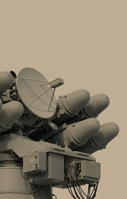 A 3D render or photograph of a military defense system featuring a satellite dish/radar alongside multiple missile launcher tubes, set against a beige/sand background.
