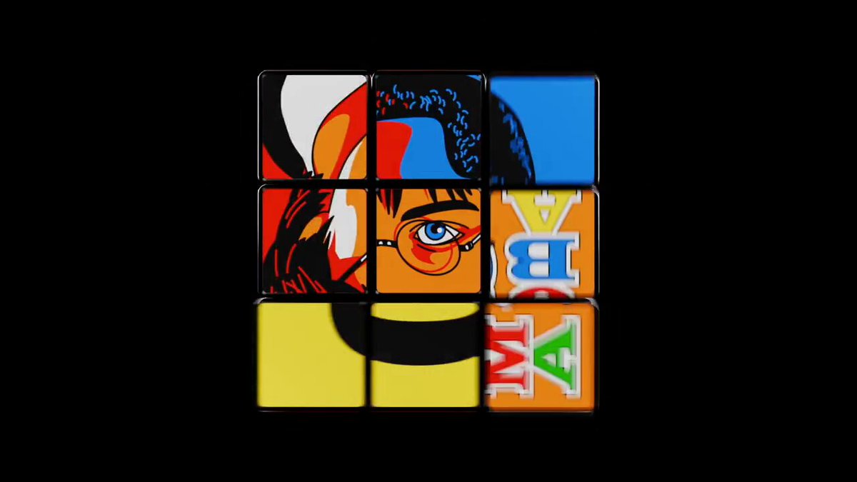 The image features a Rubik's cube with a face drawn on each of its sides, giving it an artistic appearance. The cube has six faces, each displaying a different design or pattern. The colors used for the faces are orange, yellow, blue, green, and purple. The cube is set against a black background, which contrasts with the colorful faces and makes them stand out even more.