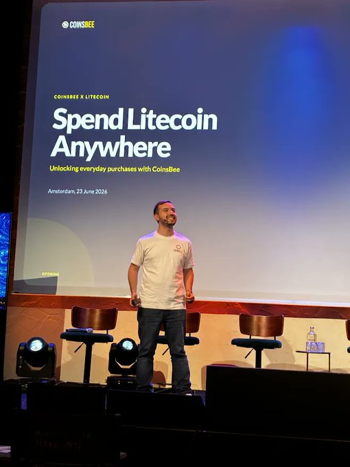 Speaker on stage presenting 'Spend Litecoin Anywhere: Unlocking everyday purchases with CoinsBee' at a CoinsBee x Litecoin event in Amsterdam, 23 June 2026.
