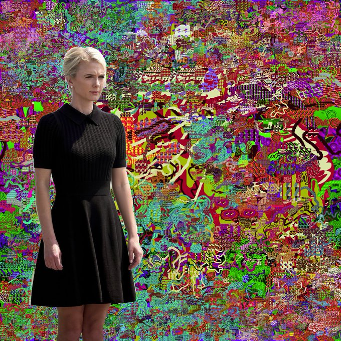 A woman with a displeased expression wearing a black top and skirt stands in front of a vibrant, multicolored psychedelic background.