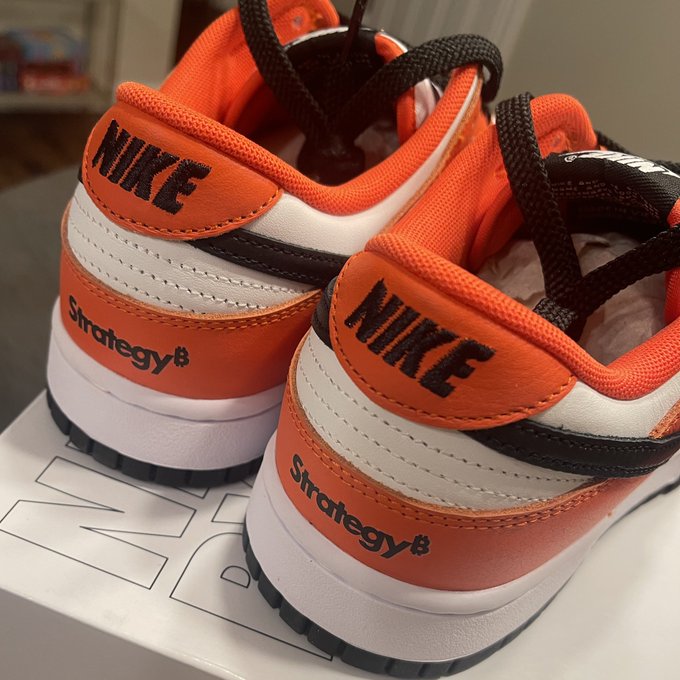 A pair of orange and white Nike Dunk Low sneakers with "NIKE" and "Strategy8" text on the heels sits atop a Nike box, visually echoing the post's reflection on clear market signals for tickers $MSTR and $STRC.