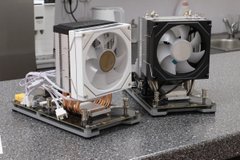 Two assembled Braiins Forge Axe ASIC miners sit side-by-side on a lab bench, showcasing the compact open-frame design with white cooling fans and exposed circuit boards. The image previews the hardware being preordered for $179 at braiinsforge.com, emphasizing the DIY build-ready form factor of the mining units.