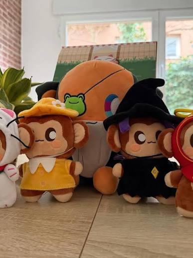 A collection of small plush toys, including monkeys in costumes and a basketball, arranged on a tiled floor.
