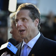 Former New York Governor Andrew Cuomo speaks during an interview, as a CNBC microphone is held up to him. The accompanying caption highlights his call for the passage of the CLARITY Act, warning that failing to do so would allow Europe and Asia to outpace the U.S. internationally.