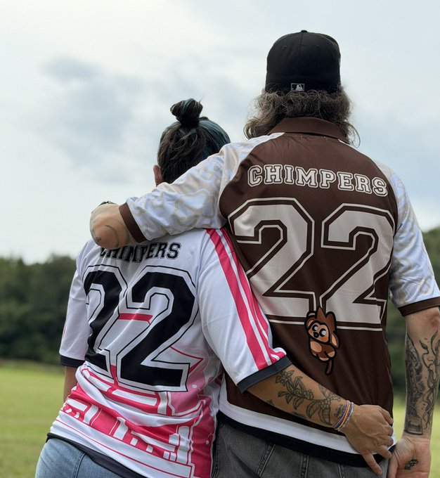 Two people wearing matching 'CHIMPERS' jerseys with the number 22, embracing from behind in an outdoor setting.