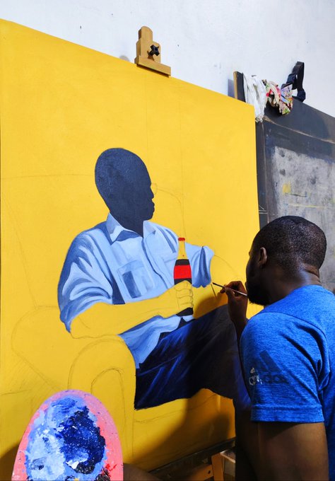 An artist in a blue shirt carefully paints a portrait of a faceless figure in a light blue shirt holding a Coca-Cola bottle against a vivid yellow canvas, embodying the post's message about how ambitious projects begin as rough sketches and imaginative visions before they're brought to life.