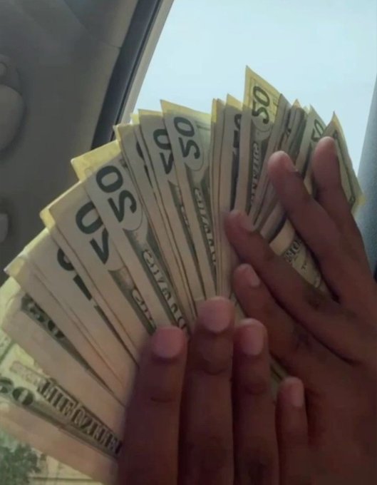 A fan of $50 US bills fanned out between two hands is displayed inside a vehicle, accompanying a cryptocurrency giveaway post promising two winners a $50 prize in exchange for liking, retweeting, and dropping their Solana (SOL) wallet address within 24 hours.