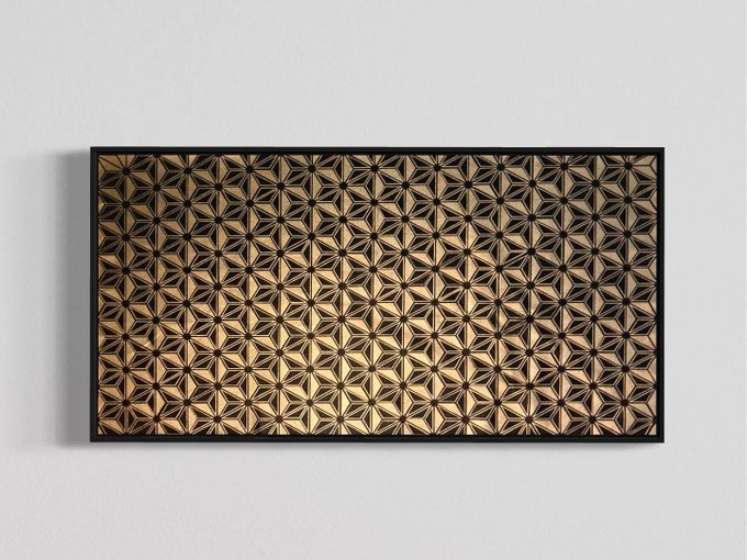 A framed piece of geometric wall art featuring an intricate pattern of interlocking stars in gold and black tones, mounted on a white wall.