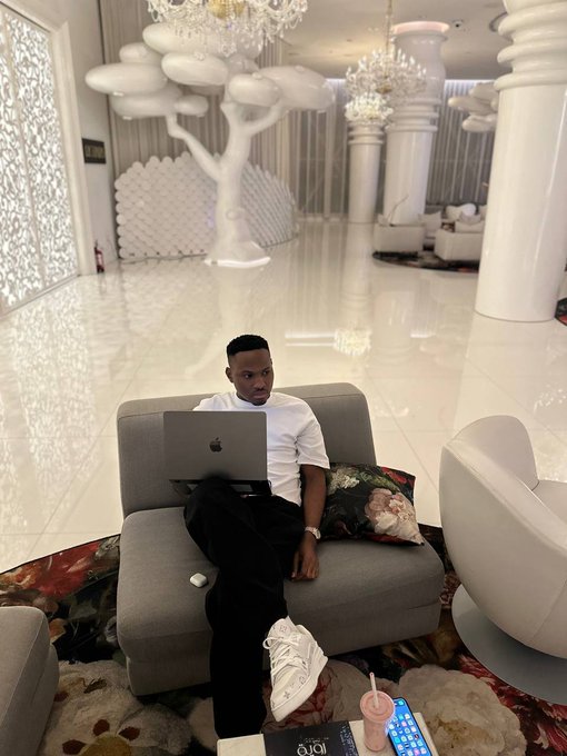 A trader relaxes on a couch with his MacBook in a luxurious, chandelier-lit lounge, bidding "Good night traders, rest peacefully—every challenge today is a lesson for tomorrow."

Visible text includes an Apple MacBook and a "100 IQ" book on the coffee table.