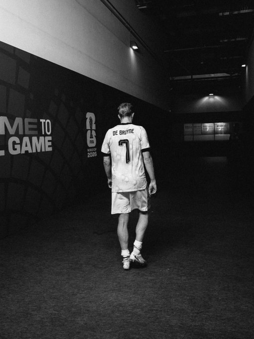 A black-and-white photo of a soccer player wearing a jersey with 'DE BRUYNE' and the number '7', walking through a tunnel.