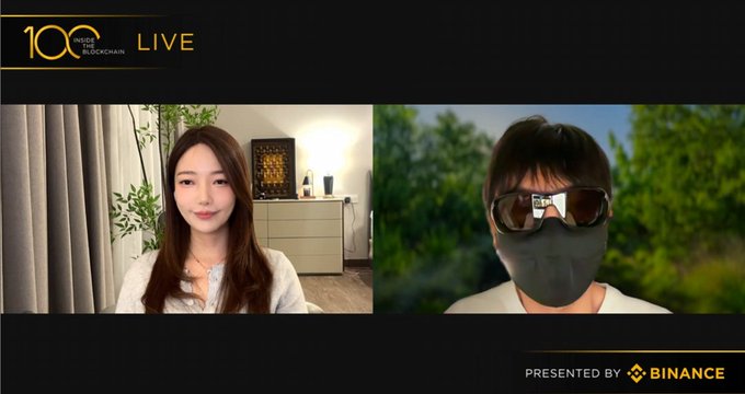 A live video stream titled 'INSIDE THE BLOCKCHAIN LIVE' presented by Binance, showing two participants on a split-screen video call, one woman in a room and one masked individual outdoors.