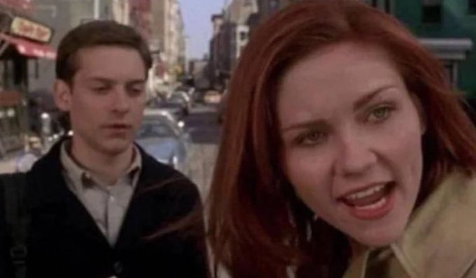 A scene from a movie or TV show featuring a young man (Tobey Maguire) and a red-haired woman (Renee Zellweger) on a city street.
