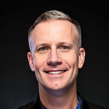 A professional headshot shows a smiling man with short graying hair and blue eyes, wearing a dark shirt against a black background. The image appears to serve as a portrait of a company executive or spokesperson associated with The Smarter Web Company ($SWC) and their recent $282 million capital reduction announcement related to a UK Bitcoin-backed perpetual preferred stock initiative.