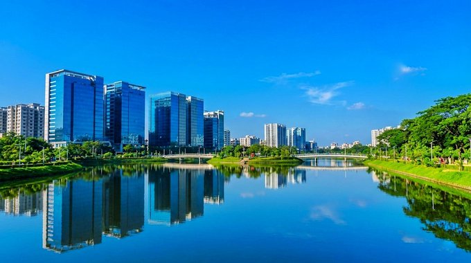 The image shows a cityscape with tall buildings, including skyscrapers, reflecting off the water below. The scene captures the beauty of nature alongside urban development. The photo emphasizes the importance of meaningful action over sheer quantity, as there are many users on the network but low-quality participation does not yield significant results.