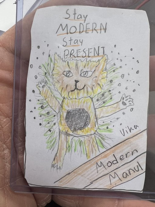 A child's hand-drawn sketch of a yellow cat-like creature, titled 'Stay MODERN Stay PRESENT' with the name 'Vika' and label 'Modern Manul' on the page.