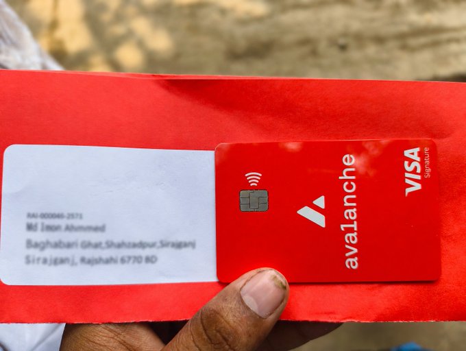 The image shows a person holding an Avalanche credit card, which is red with white text. The person's hand is visible as they hold the card against their body. The post mentions that the card has arrived safely and smoothly, indicating that the user had no issues with receiving or processing the card. This implies that the user may be excited to use the card for purchases and transactions.