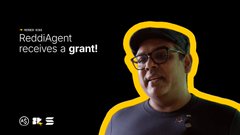 A thumbnail-style image with a man wearing glasses highlighted by a yellow outline, featuring text 'RedditAgent receives a grant!' alongside Reddit and other platform icons.