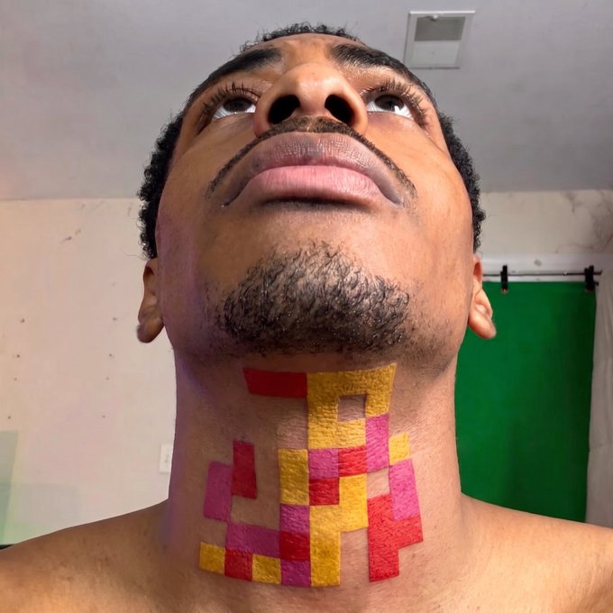 A man shows off a colorful pixelated neck tattoo featuring a checkerboard-style design in red, yellow, and pink, resembling a digital "credit" token. The geometric aesthetic mirrors the signature style of Jack Butcher's iconic NFT artwork, symbolizing a permanent tribute to the digital collectible.