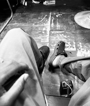 A person sits with their worn sneakers and denim-clad legs visible against a scuffed wooden floor, with a small electronic device resting nearby. The caption "goodnight y'all — I'm going for #unchainsummer2026" suggests they're winding down for the night, gearing up for a relaxed summer vibe.
