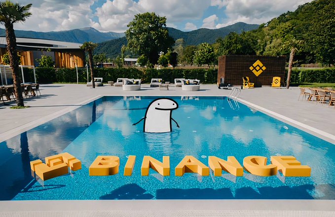 A Binance-branded swimming pool features a large Binance logo mascot floating in the water, with the words "NO BINANCE" spelled out in yellow 3D letters in the foreground. The sunny poolside setting with mountains in the background matches the post's "Sunshine. Pool. #Binance. Summer mode: ON" theme, showcasing the crypto brand in a fun, leisure-oriented summer scene.