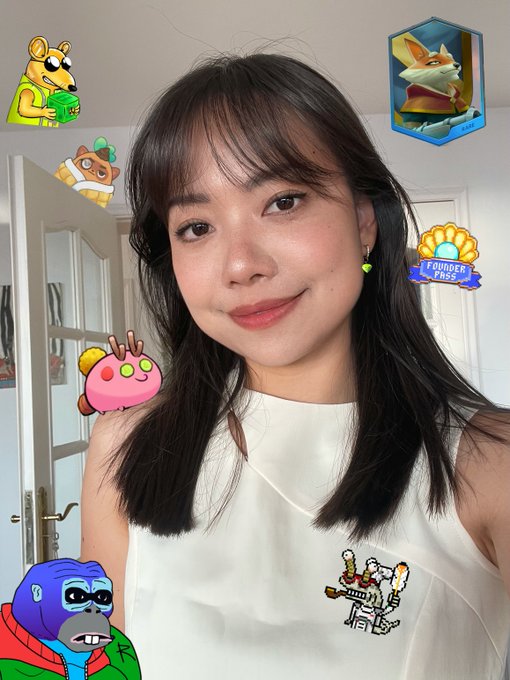 A selfie of a young woman with long dark hair and bangs, wearing a white sleeveless top featuring a SpongeBob and Squidward graphic, decorated with various stickers and NFT characters including a "Founder Pass" badge and a monkey mascot. The image aligns with her post promoting Ronin blockchain's dominance in web3 gaming and her @RonkeOnRon NFT collection.