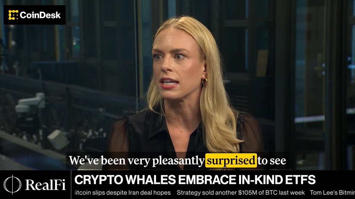 A blonde woman in a black blouse speaks in a CoinDesk interview, with the headline "CRYPTO WHALES EMBRACE IN-KIND ETFS" displayed below, illustrating Grayscale's Krista Lynch discussing how crypto-native investors are adopting in-kind ETFs for tax benefits, estate planning, and diversified custody.