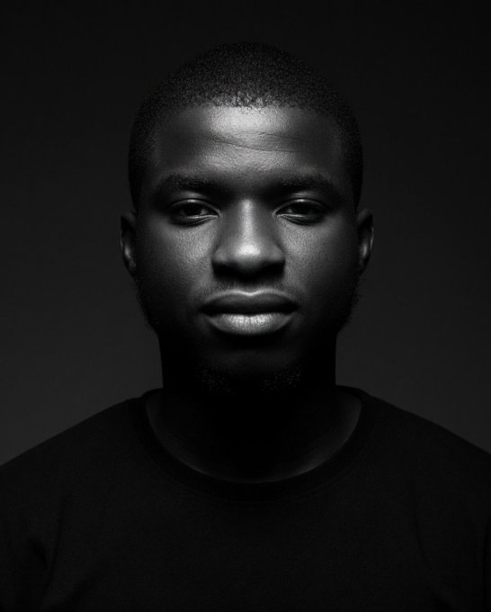 The image features a man wearing a black shirt against a dark background. The photo has been edited or altered to emphasize the subject's face while removing other elements from the scene. The focus of the image is solely on the man, with no other objects or distractions present.