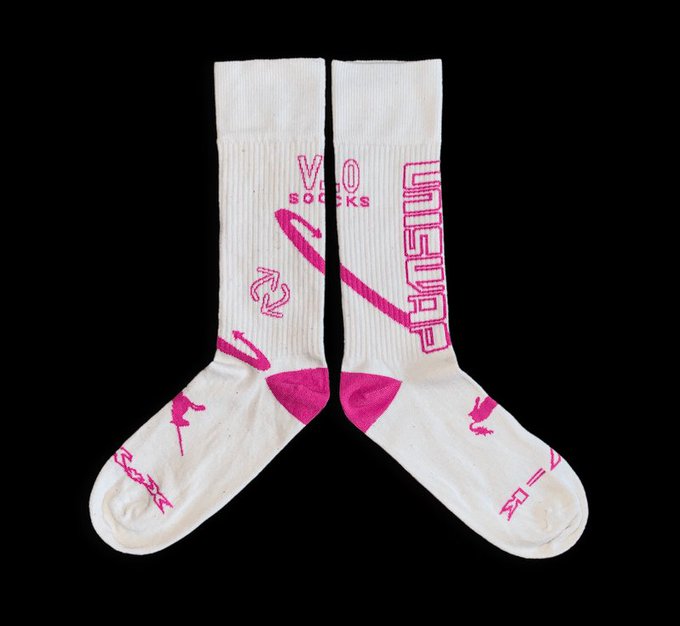 A pair of white crew socks with hot pink accents and 'VIO SOCKS' branding, featuring small character illustrations and decorative graphics, displayed against a black background.
